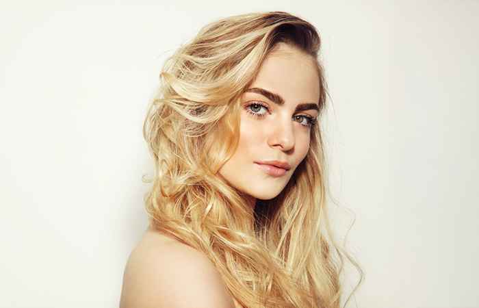 Woman with layered blonde hair and dark roots