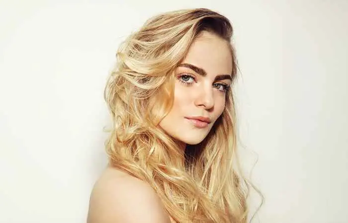 Woman with layered blonde hair and dark roots